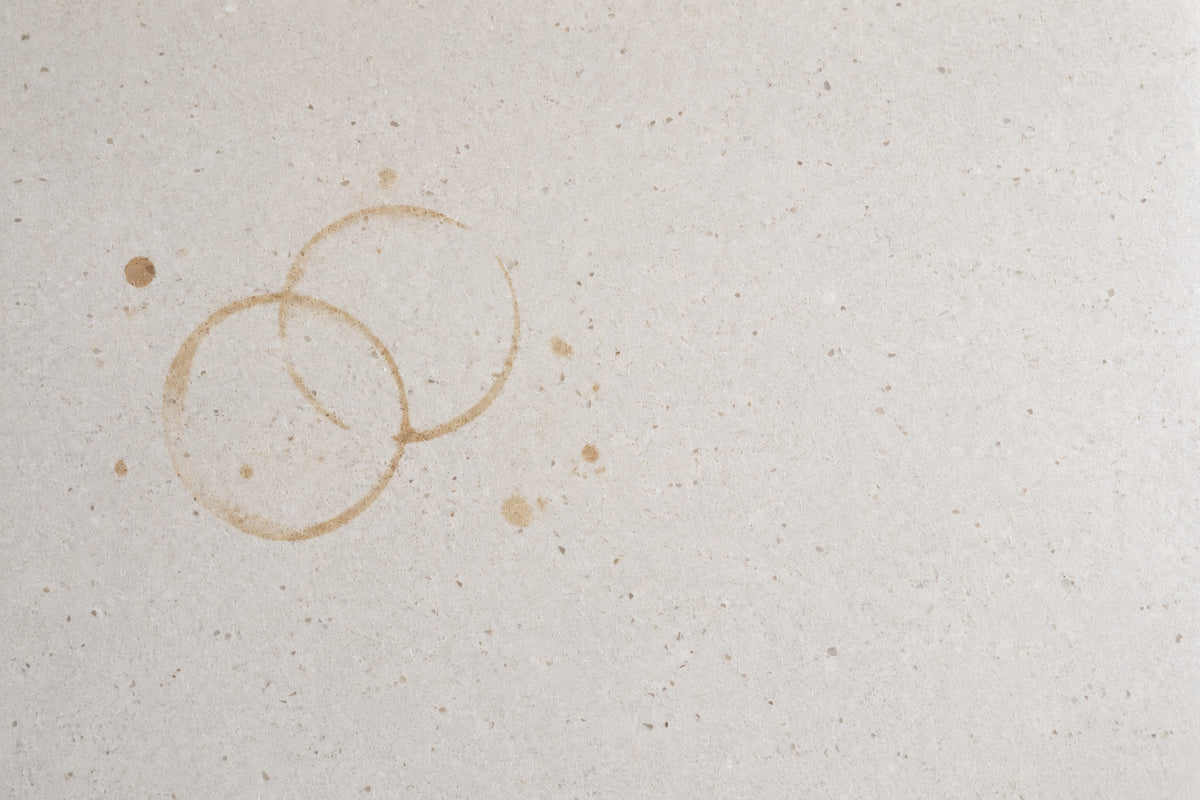 The same worktop with two overlapping brown coffee cup rings and dried splashes